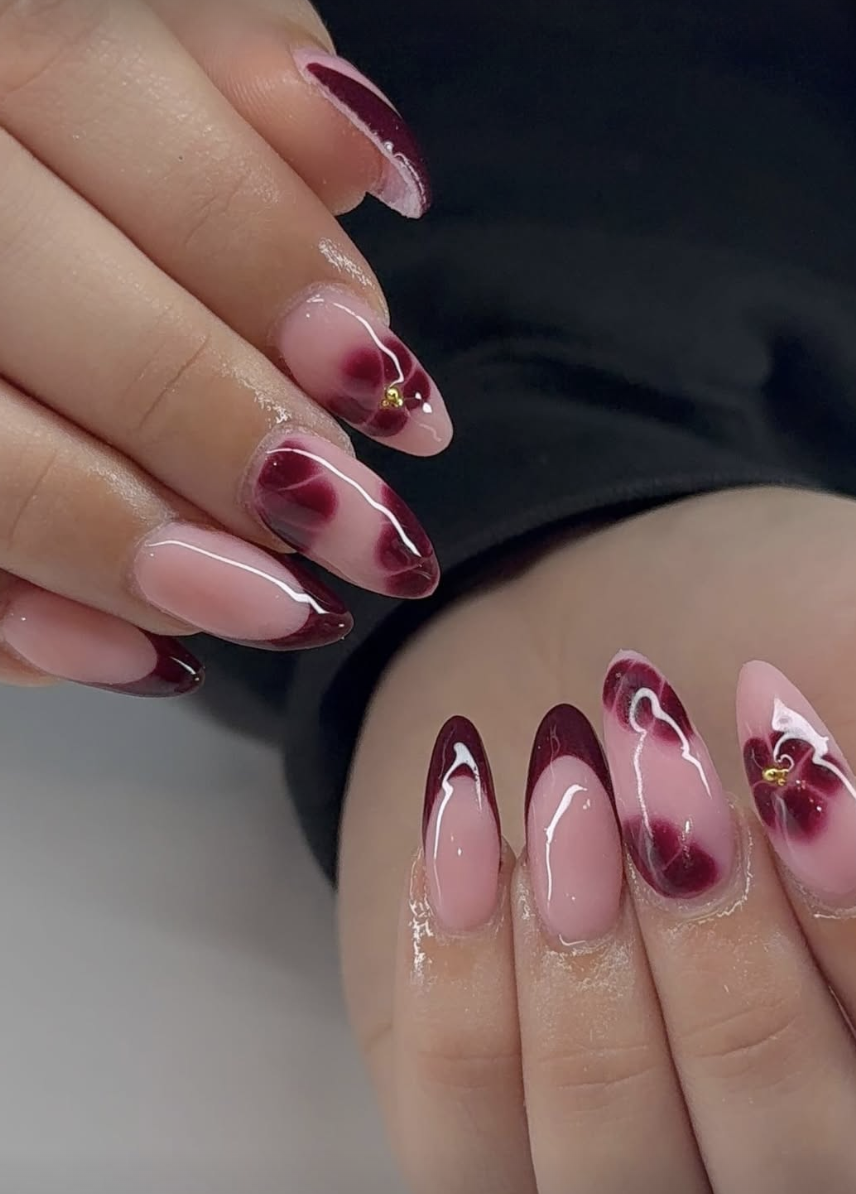 Almond nails with burgundy marble French tips and floral accents